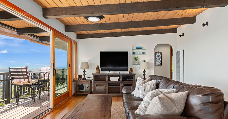 interior view of living area looking out on deck and views of homes and nature below. 