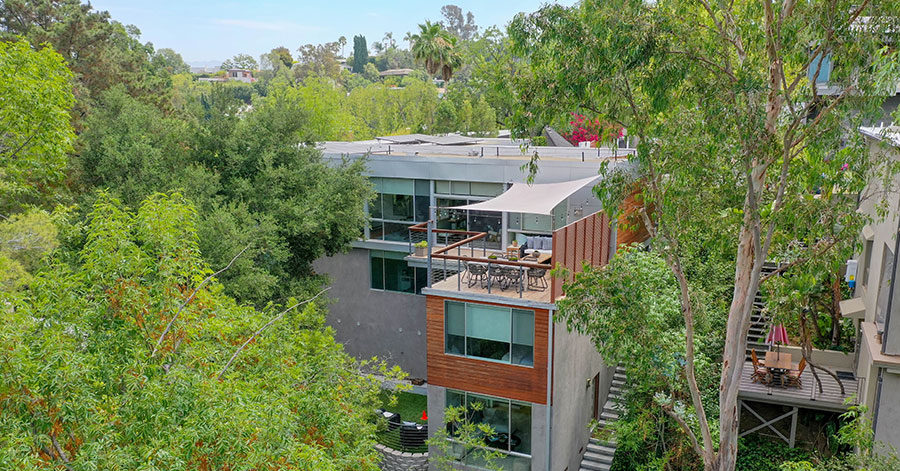 aerial view of hillside home nestled among lush green trees. 