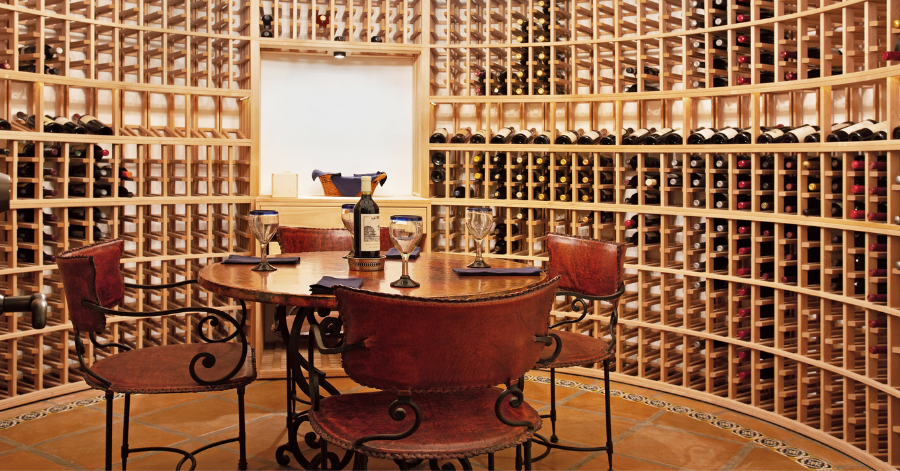 Wine tasting table in circular room where walls are filled with wine bottles 