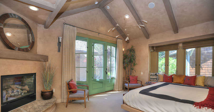 master suite with large green windows and high beamed ceilings. 