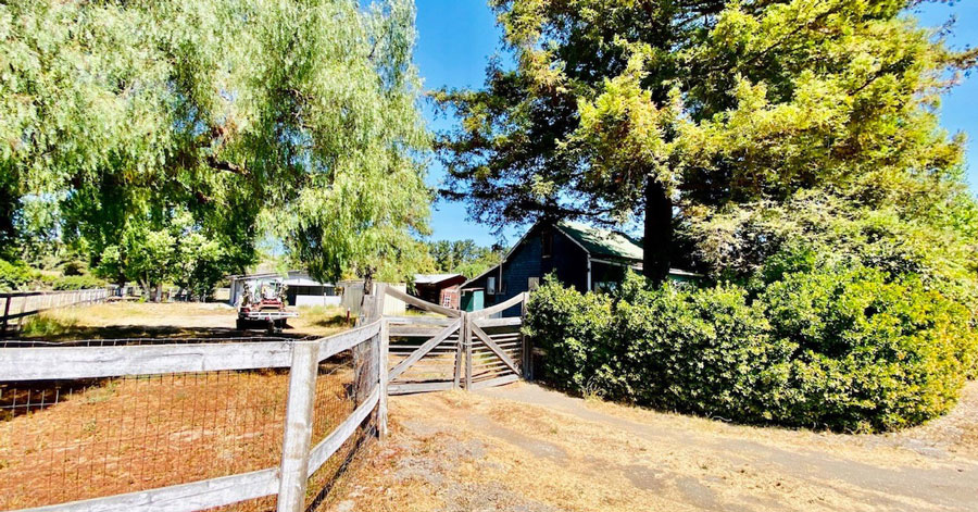 Ranch home surrounded by trees and wooden fences 