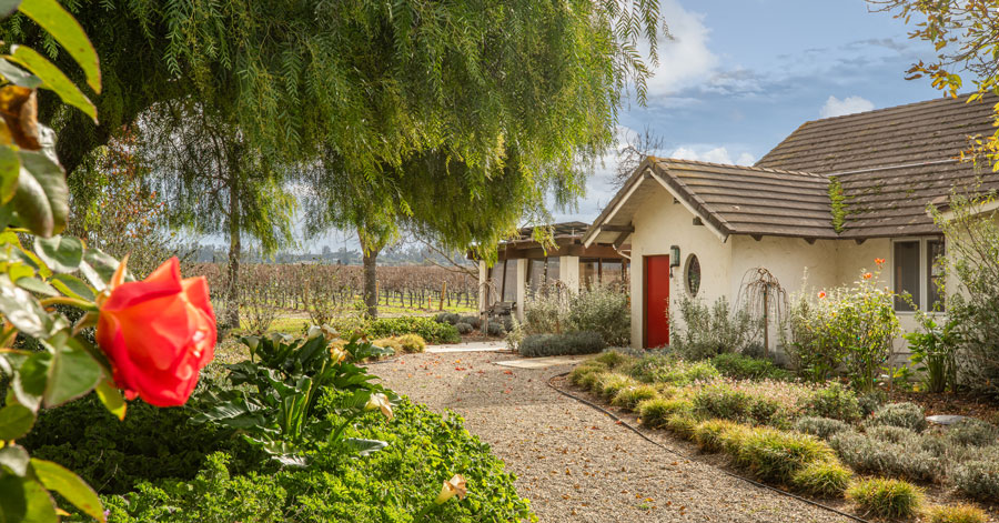 Ranch-style home with red door and large red rose 