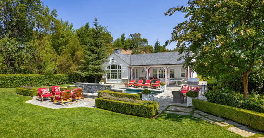 beautiful guest house surrounded by lush green landscaping and a pool 