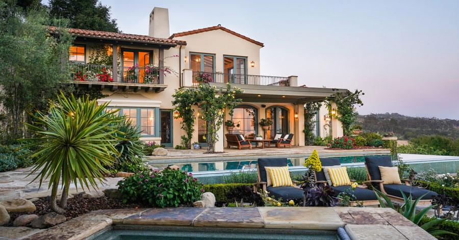 View of beautiful home from across jacuzzi and pool. 