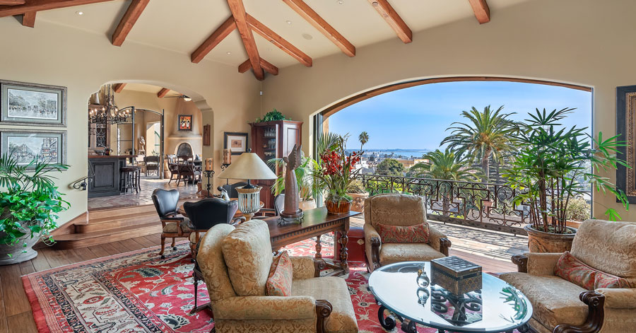 Interior shot of living room with high beamed ceiling and a large arched doorway that opens up to patio taking up full length of the wall. 