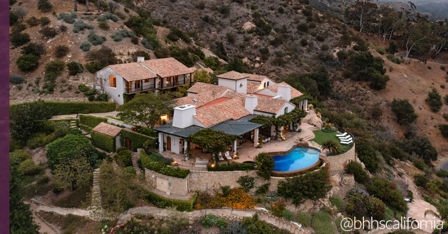 aerial view of a home with a guest house and infinity pool