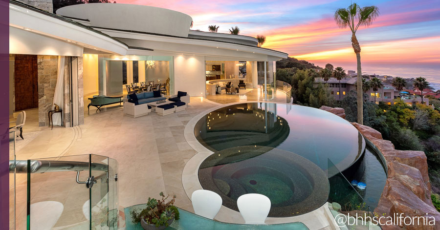 luxurious home with indoor-outdoor living features such as walls of glass doors, a large patio, and infinity pool