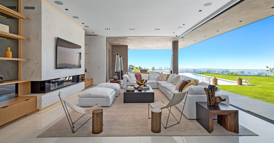 Living room with indoor-outdoor living. Walls of doors are open to the outside lush grass and city views. 