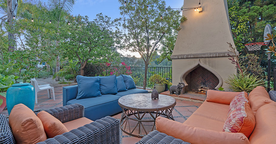 Outdoor patio area of Misha Collins home with prominent fresstanding fireplace and chimney