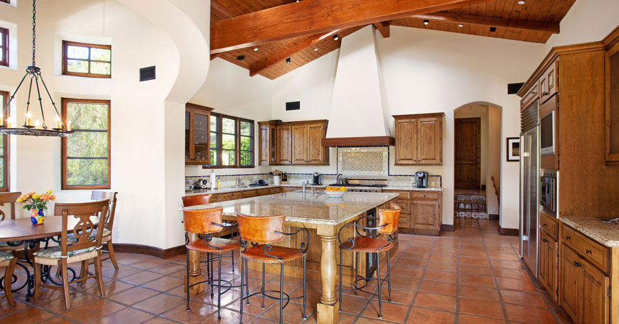 Spanish style kitchen with brown wood cabinets and red tiled floors