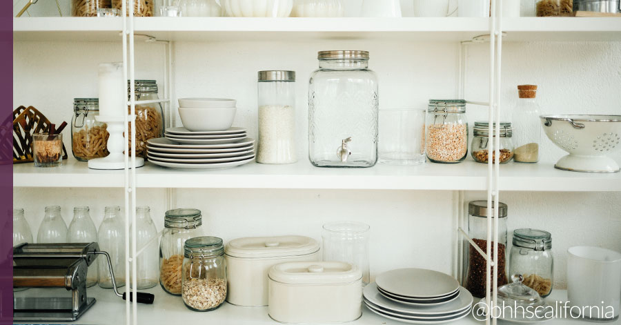 Photo of pantry cabinets that show great kitchen organization using jars, containers, and neat stacks of dishes. 