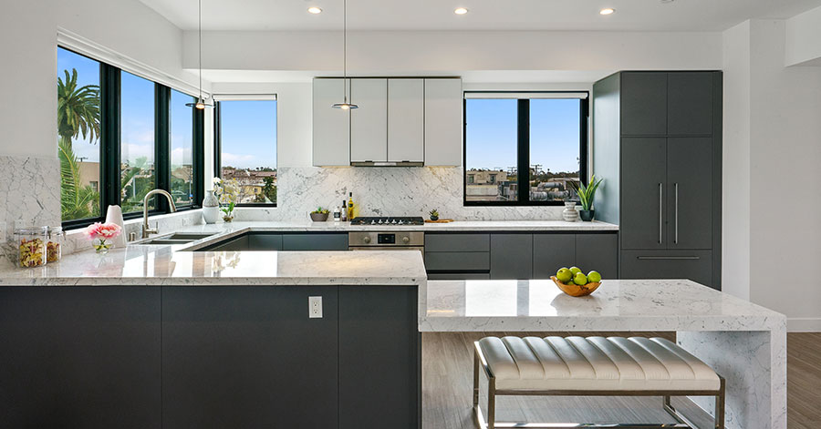 Luxury kitchen with lots of natural light, dark grey cabinets, and white counter tops