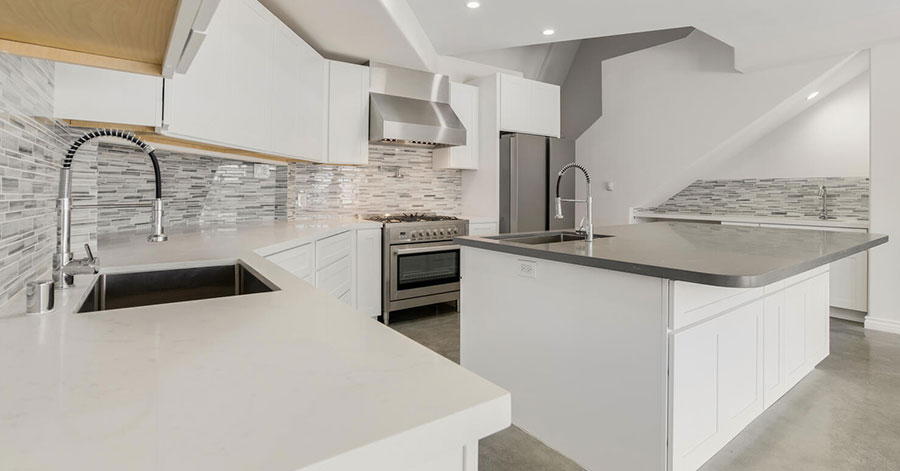 Spacious modern kitchen with stainless steel appliances, grey tiled backsplash, and large kitchen island 