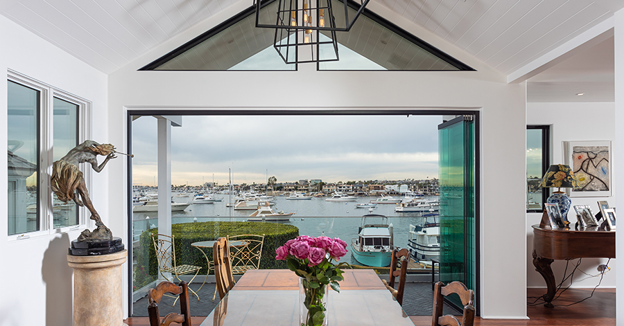 Interior of home looking out open doors at Newport Harbor from home's dining table. 