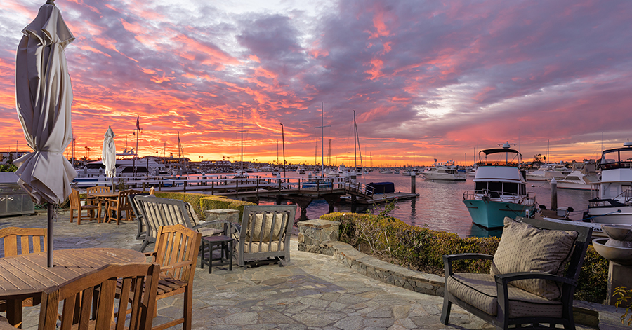 Sunset skies over Newport Beach bayfront home and the patio, harbor. 