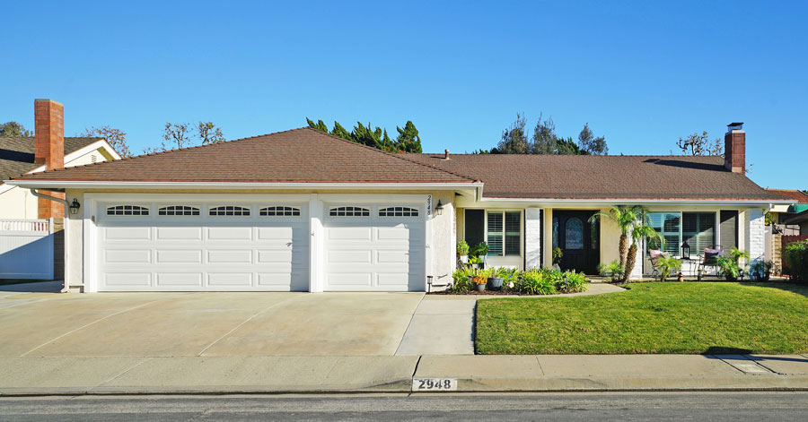 remodeled pale yellow home under blue sky with green grass and landscaping