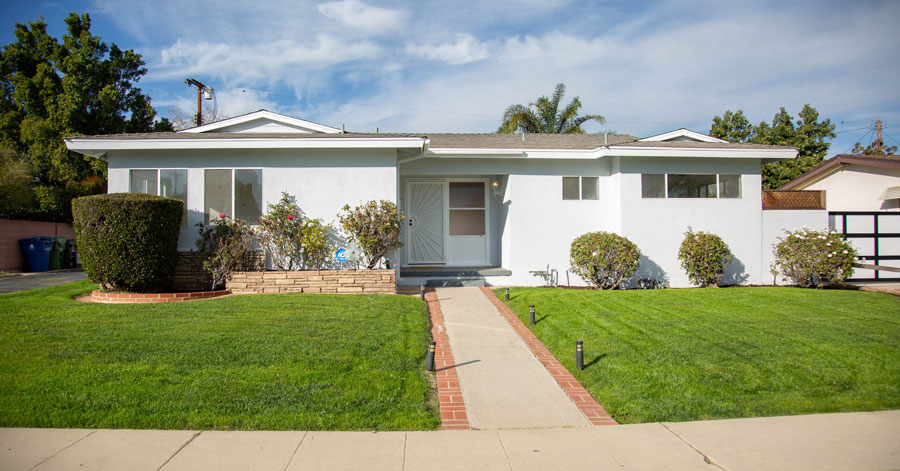 remodeled white house with shrubs and bushes under blue sky 