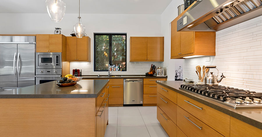 Modern kitchen with grey countertops stainless steel appliances and brown cabinets 