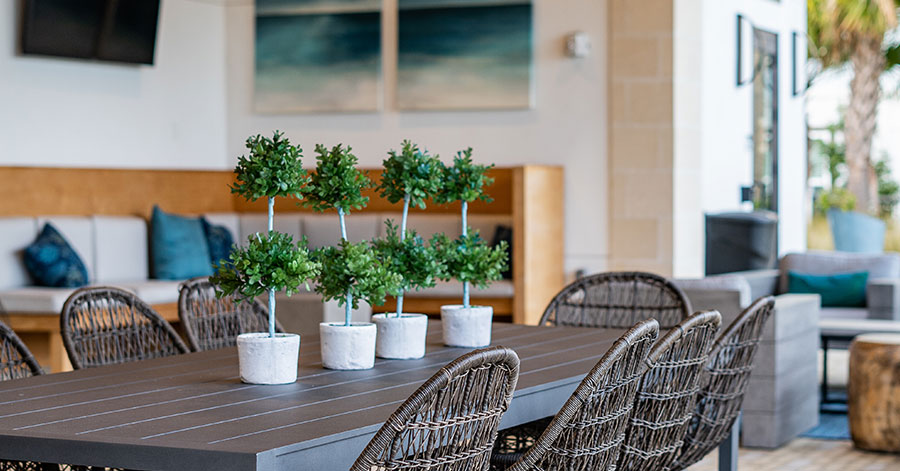 Outdoor patio with dining table in foreground an couches in background 