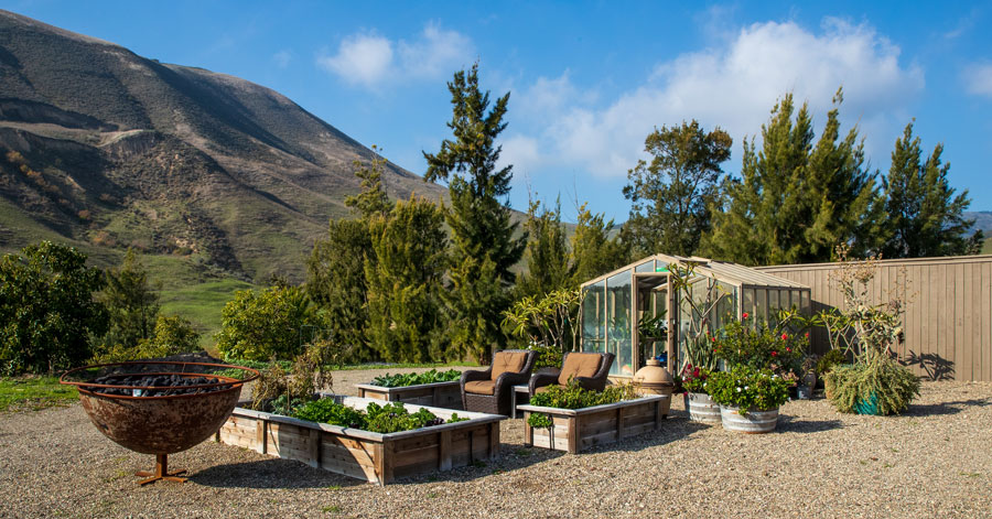 Southern California garden with raised planters and a greenhouse. 