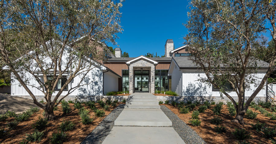 Entrance of a Hidden Hills home lined with small shrubs, mulch, and trees 