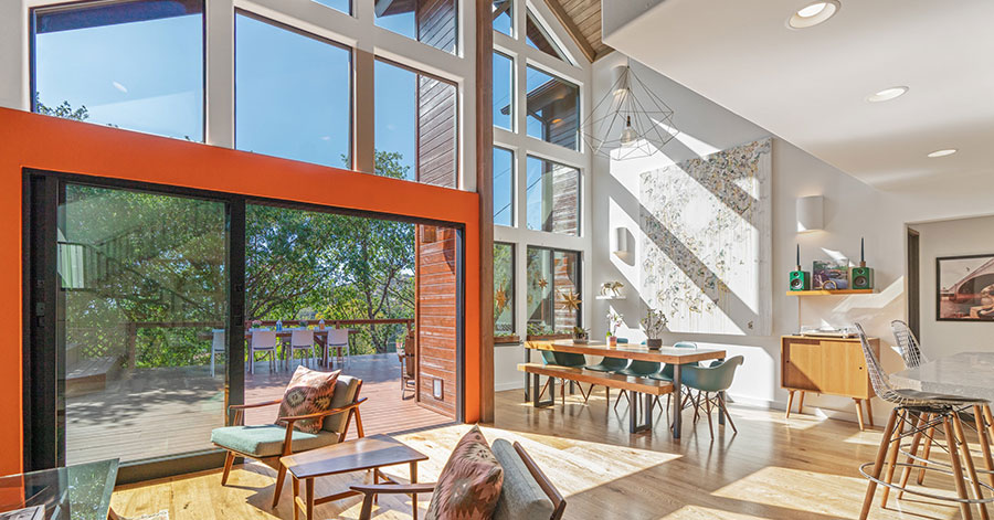 View from living room through large wall of glass windows to back deck 