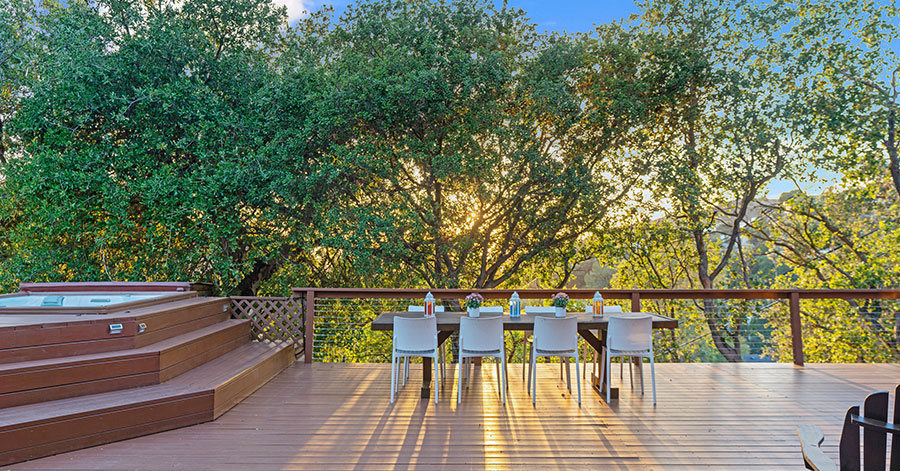 View from home of deck, raised hot tub, and lush green trees that provide privacy 