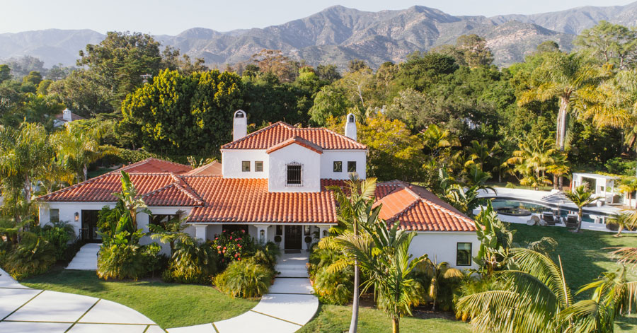 aerial view of white spanish style home with red tile roof 