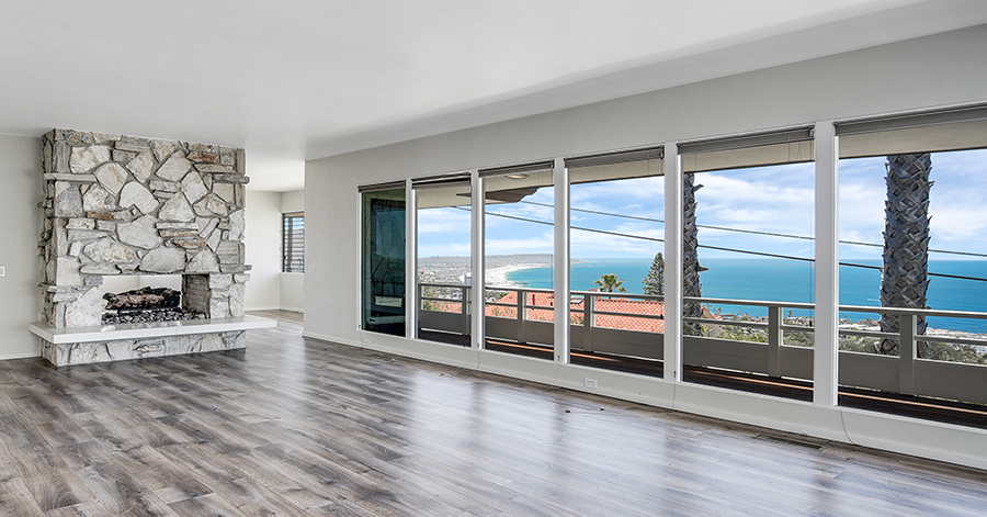 Empty living room with stone fireplace and modern flooring with a view of the ocean