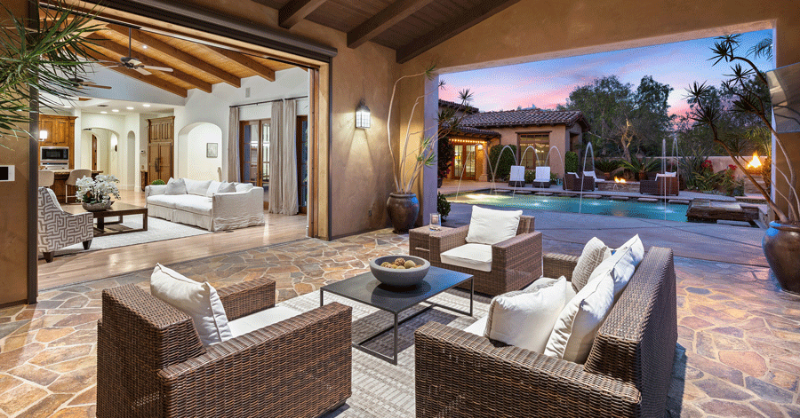 Covered patio with pool, fountains, and fire pit in the background 