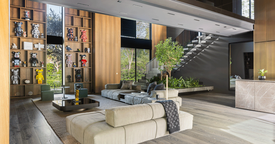 Large modern living room with wall of bookshelves covered in collectible figurines 