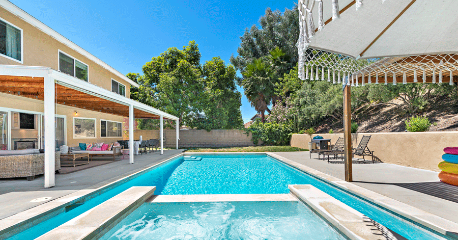 Pool and spa surrounded by covered seating areas with grassy area 