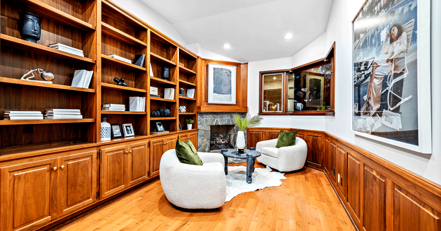 sitting room with shelves along one wall leading to a stone fireplace 