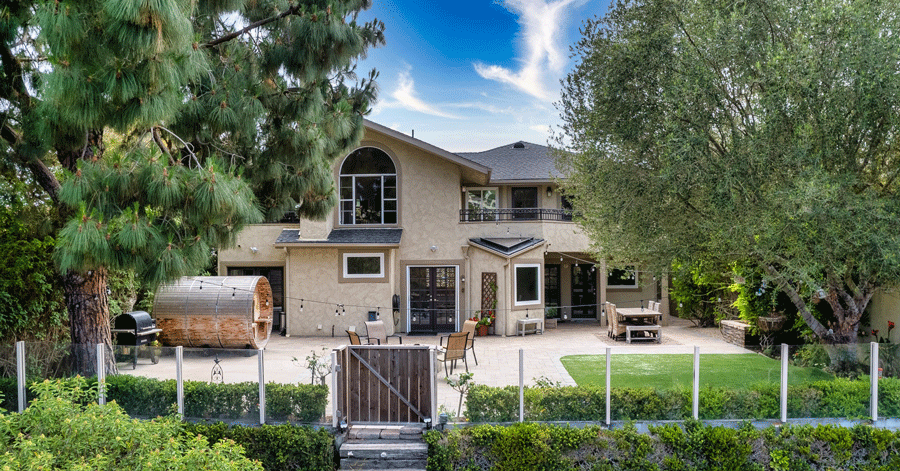 View of home's backyard with sauna and patio with grassy area and dining table 