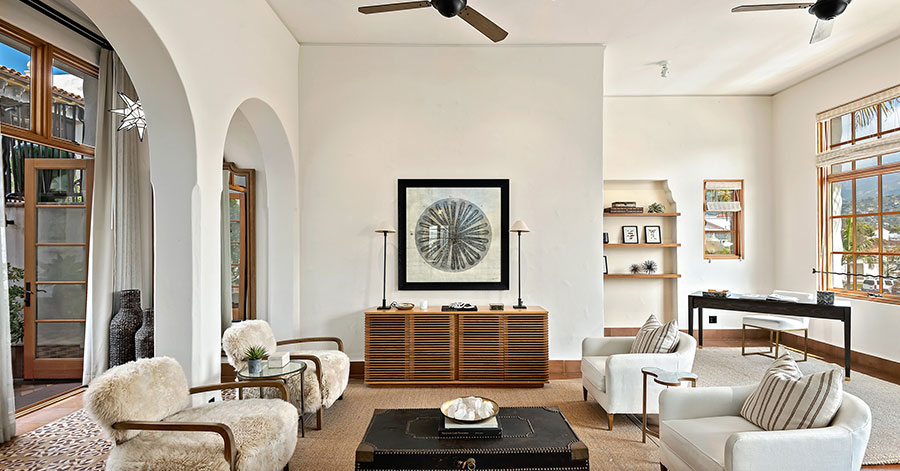 modern living room with high ceilings and archways leading to patio. small desk in corner of room by built in shelves