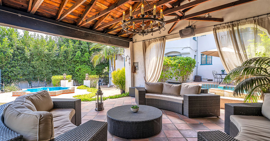 Covered outdoor seating area with couches and a chandelier 