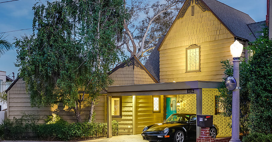 Exterior of former home of The Doors’ John Densmore with black luxury car in carport 