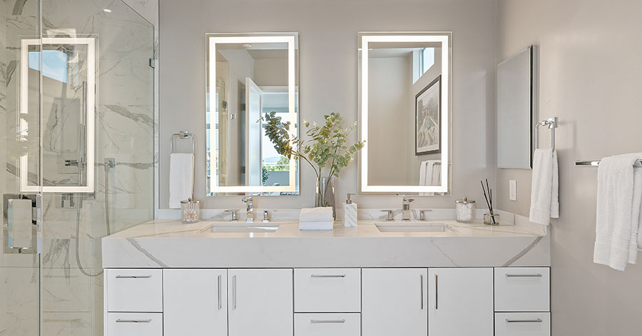 Luxury primary suite bathroom with white marble and two sinks 